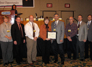 Nebraska Farm Loan Programs accepts a certificate of appreciation for achieving the highest dollar amount and number of direct loans obligated. (From left) Cindy Porter, Farm Loan Reviewer; Tim Reimer, Farm Loan Specialist; Mike Eller, District Director; Teresa Lasseter, Administrator; Rich Barta, Farm Loan Chief; Bob Meints, Farm Loan Specialist; Mark Wilke, Farm Loan Specialist; Paul Cernik, Farm Loan Specialist.